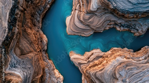 Aerial view of vibrant blue water winding through sculpted, textured canyons