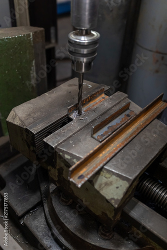 Фотография Macro shot of a drill bit penetrating a metal sheet securely clamped in a bench vise during precision metalwork