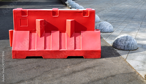Bild auf Leinwand Bright red temporary traffic barrier positioned on an urban street for traffic control and road safety