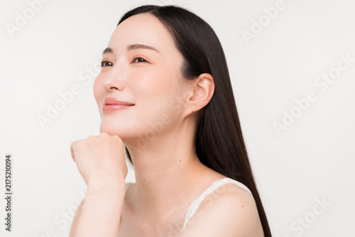 顔に手を添える黒髪ストレートヘアの若い日本人女性。スキンケアイメージ。