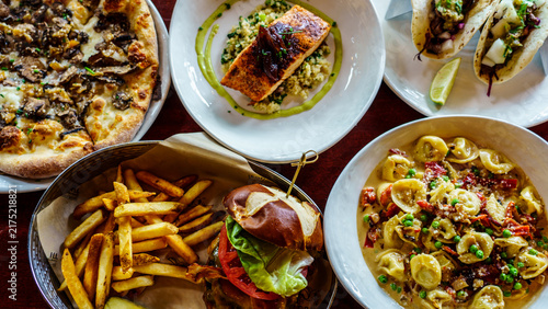 Foto Dining table filled with various dishes including pizza, fish, pasta, tacos, and