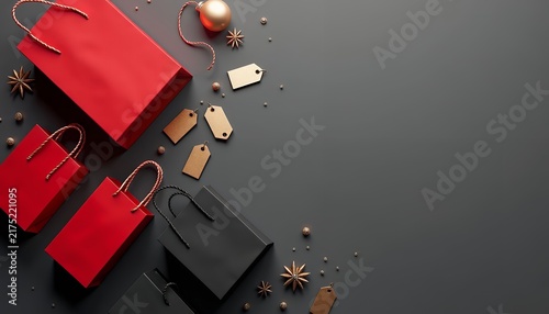 Red and black shopping bags with gold tags and star anise on a dark gray background surface