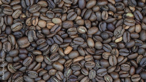Close up rotating top view of freshly roasted coffee beans forming a rich dark textured background