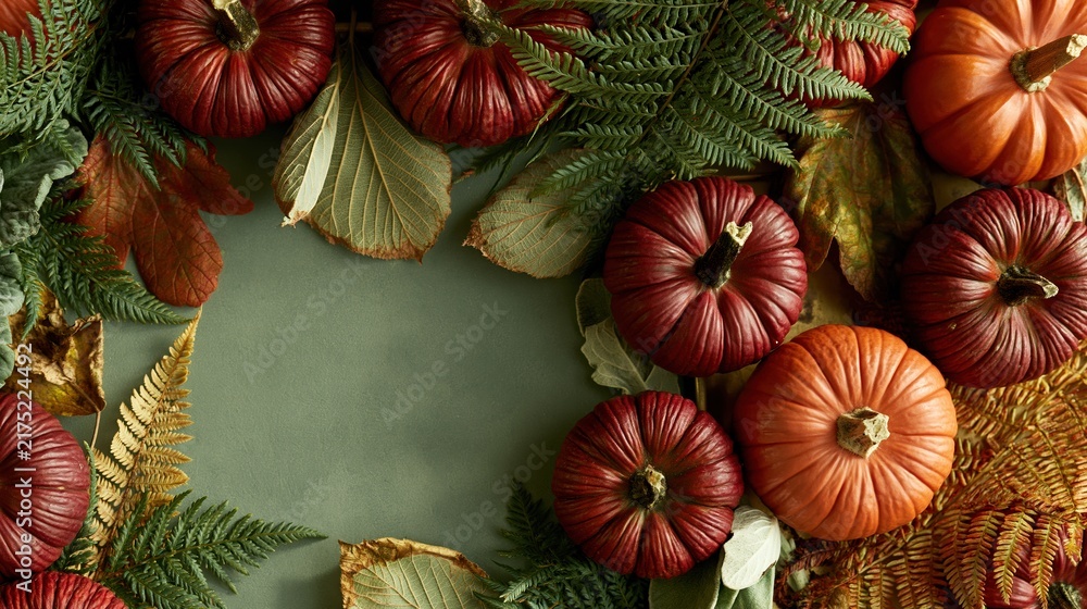 Fototapeta premium Olive green board with a border of maroon pumpkins and autumn leaves, featuring a moody, cozy atmosphere and copy space for holiday cards