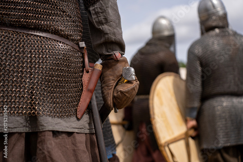 Canvas Print Medieval warrior wearing chainmail armor and leather glove holding sword hilt in sheath while standing in battle formation outdoors