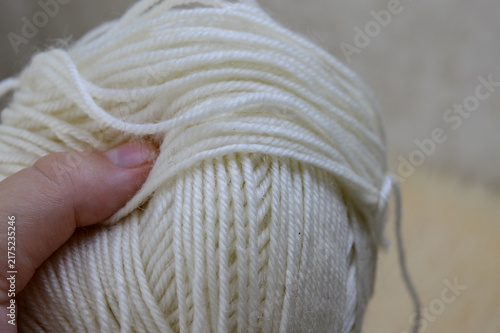 Canvastavla Woman hand holding a large skein of soft white wool yarn close-up