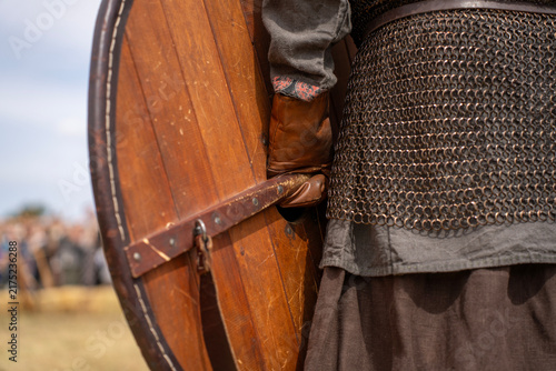 Canvastavla Medieval warrior in iron chainmail armor and leather glove holding round wooden shield from behind during historical reenactment festival