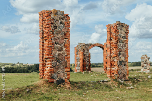 Fotografie Weathered brick-and-stone ruins rise from a grassy field, with a surviving arch