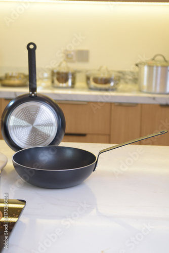 Obraz na plátně Cookware arranged on a modern stovetop, combining dark pans with a warm kitchen interior for a home cooking lifestyle scene