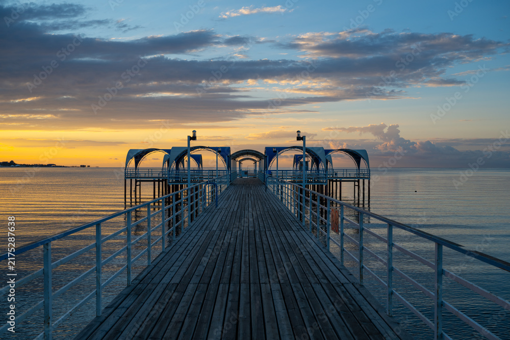 Fototapeta premium A metal pier set against the backdrop of a picturesque sunrise over Lake Issyk-Kul, near the Kyrgyz city of Cholpon-Ata.