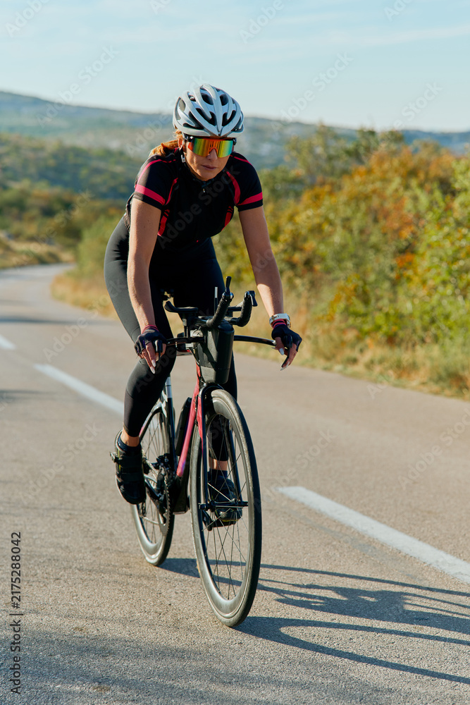Naklejka premium Female Cyclist Training on Open Road With Helmet and Sunglasses - Outdoor Road Cycling Fitness