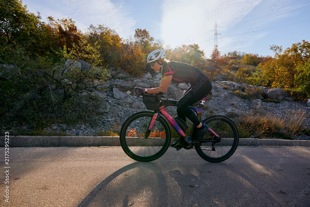 Naklejka premium Female Cyclist Training On Road Bike During Autumn Ride Through Rocky Countryside