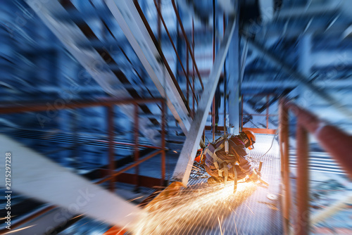 Canvas Print Industrial worker cutting metal with sparks on elevated platform for safety and