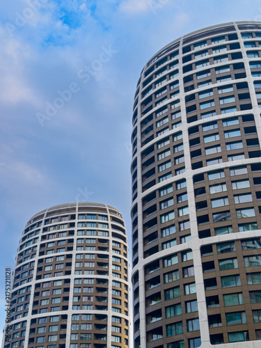 Tall buildings under a cloudy sky. Two tall buildings stand against a cloudy sky. The setting shows urban architecture with many windows.
