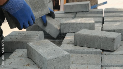 Construction workers hands stacking gray bricks from a pallet, bricklaying and wall construction, mason in blue gloves at work, masonry construction, building materials, skilled manual labor