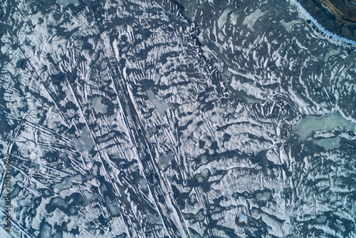 Bild auf Leinwand Snowy eroded surface of industrial slag heap with frozen ridges and gullies, top