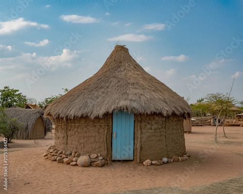 Canvastavla Traditional round hut with a thatched roof and a light blue wooden door in a rur