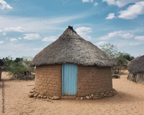 Fotografía Traditional round hut with a thatched roof and a light blue wooden door in a san