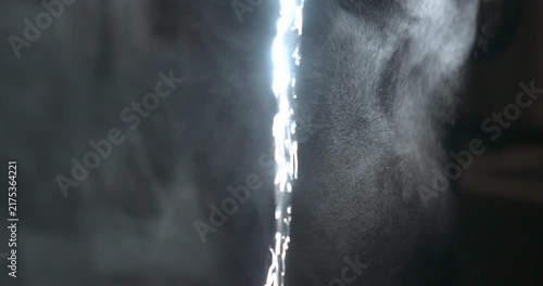 Close-up detail of flowing water stream, cinematic dark shot