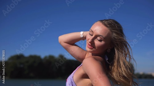 Romantic Female Model In Revealing Short Summer Dress On Riverside Beach.  She Smiles And Turns Gracefully As Her Open Shoulder Dress Flows In The Wind.