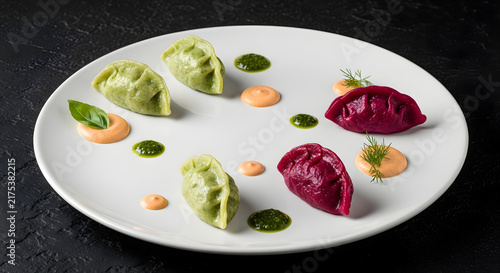 Colorful dumplings on white plate with sauces for culinary presentation
