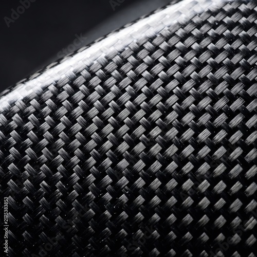 Carbon fiber weave texture showing intricate black geometric pattern with smooth glossy highlights captured in high resolution sharp macro photography detail