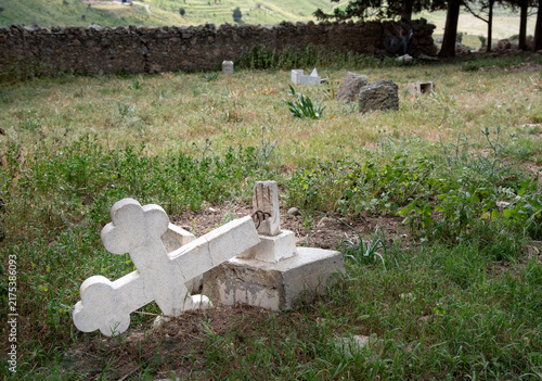 Broken white marble cross laying on the ground in a cemetery, evoking themes of loss, remembrance, and the passage of time