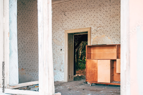 Cuadro en lienzo Old wooden sideboard inside a neglected room with damage and peeling wallpaper