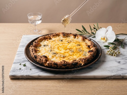 Konstfotografi Fresh baked cheese pizza on a stone board with honey drizzling