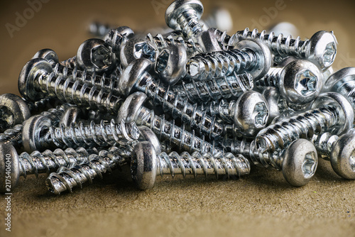 Konstfotografi Close-up of a pile of shiny metal screws with Phillips heads arranged on a textu