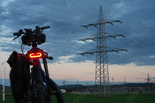 Konstfotografi Electric bicycle with a glowing red rear light stands in the foreground while po