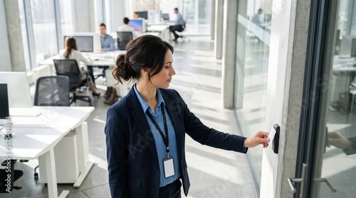 Businesswoman scanning security badge at office door access control, corporate employee using keycard reader in modern open plan workplace