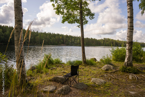 Lonely fishing chair near a forest lake