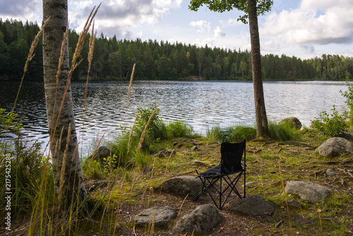 A lonely broken fishing chair by a forest lake
