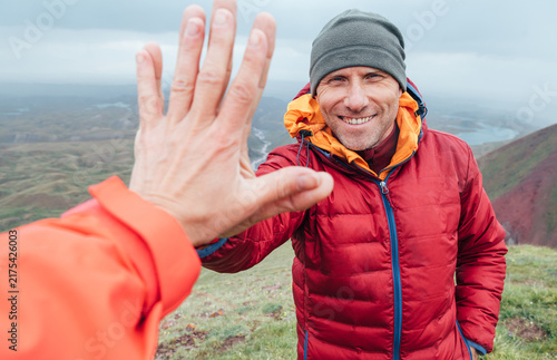 Smiling backpacker dressed orange jacket giving High Five to female mate during Himalaya valley trekking. Mera peak climbing route near the Khare settlement, Makalu Barun National Park trek in Nepal.