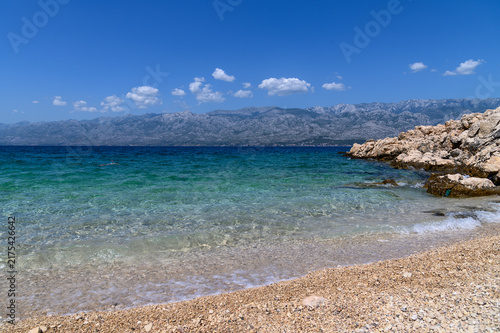 Turquoise shallow water of Bokulja beach with the Velebit mountain range across the channel, Slivnica, Croatia