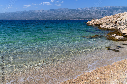 Rippled sunlight on the seabed in the clear shallows of Bokulja beach with the Velebit range beyond, Slivnica, Croatia