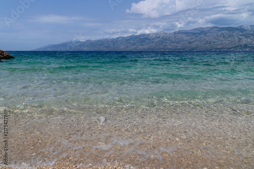 Wide view of the clear Adriatic shallows and pebble beach at Bokulja below the Velebit ridge, Slivnica, Croatia