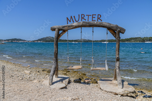 Rope swings hanging over the turquoise shallows of a quiet bay on Murter island, Dalmatia, Croatia