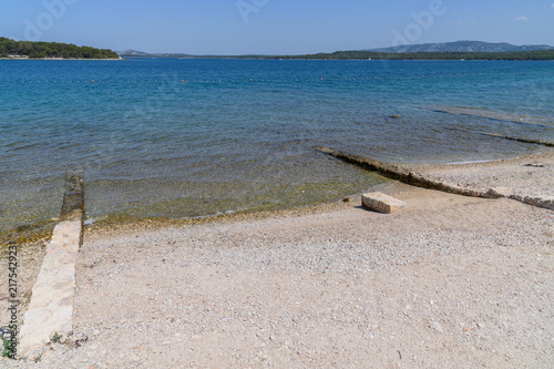 Ancient submerged stone wall running into the shallow water of a quiet Adriatic bay, Dalmatia, Croatia