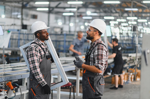 Bild auf Leinwand Factory workers discussing manufacturing pvc window frames