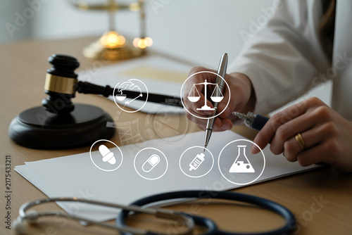 Fotografie Medical malpractice concept with judge gavel and doctor writing on medical report on office desk