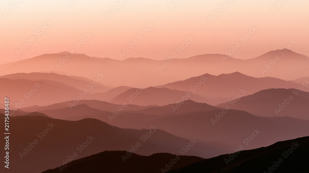 Obraz premium Warm dusk light covers a blurred horizon with layers of distant hills and mountains. The scene invites quiet reflection and a moment of pause.