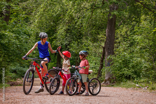 Coach and children cyclists pause on a forest trail together