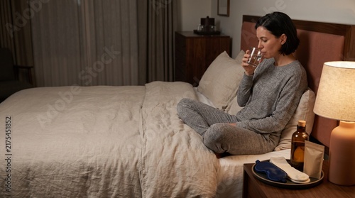 Traveler settles in with essentials beside the bed