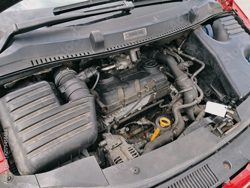 Top view of an exposed car diesel engine compartment with protective cover removed, showing internal parts, hoses, and wiring.