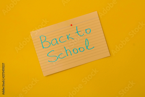 Foto Back to School Note Pinned on Yellow Wall With Handwritten Blue Ink Lined Paper Message