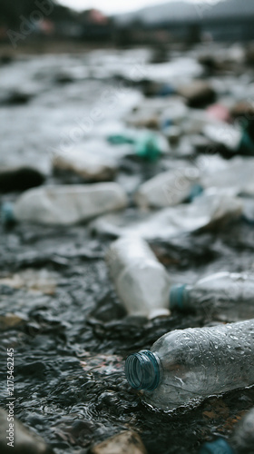 Plastic bottles littering a river, highlighting environmental pollution issues.