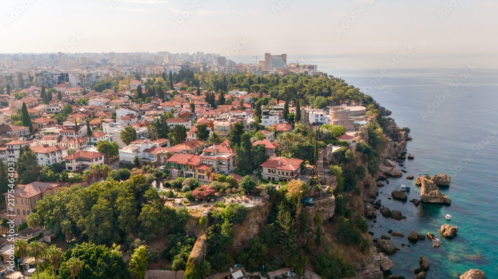 Fototapeta premium Aerial view of Antalya's Kaleici old town with red tile houses, Hidirlik Tower, lush park and rugged Mediterranean coastline