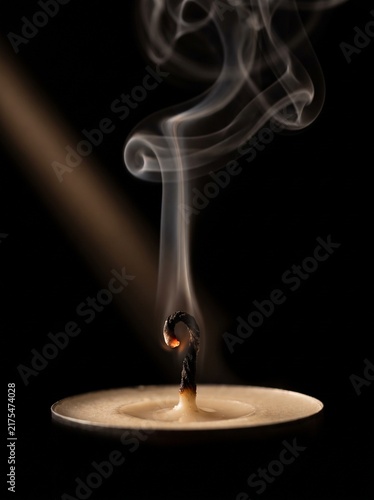 A candle snuff plume curling up from an extinguished wick